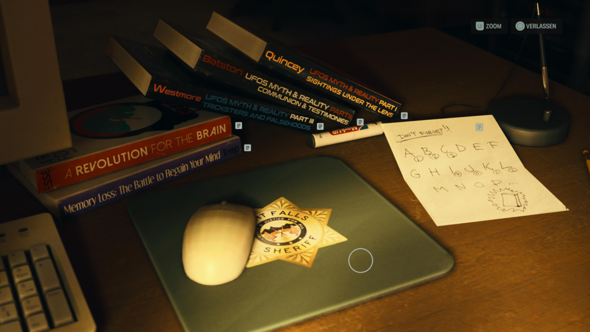 Auf einem Schreibtisch in Alan Wake 2 liegt ein Stapel Bücher und eine Notiz.