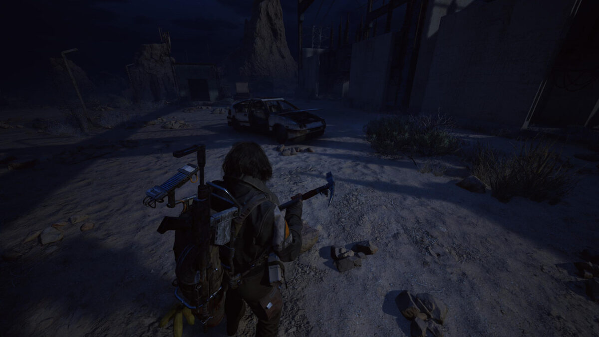 Ein Mann steht vor einem ausgeschlachteten und verlassenen Auto mit einer Axt.