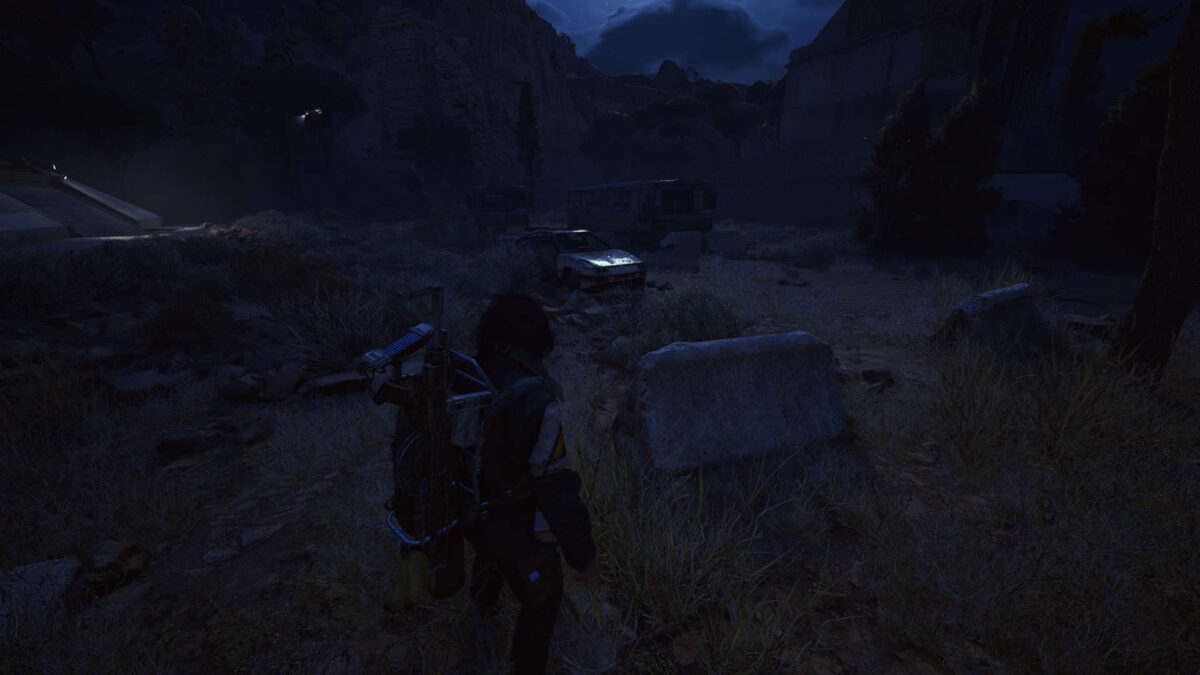 Ein Mann steht vor einem Auto, um ihn herum Steine und Felswände.