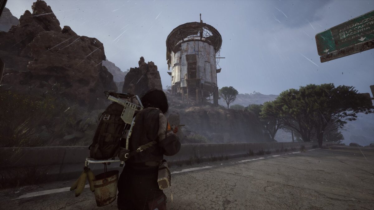 ARC Raiders: The player character approaches the northern outpost in the rain, passing a rusty water tower in a rocky gorge of the Dam Battlegrounds.