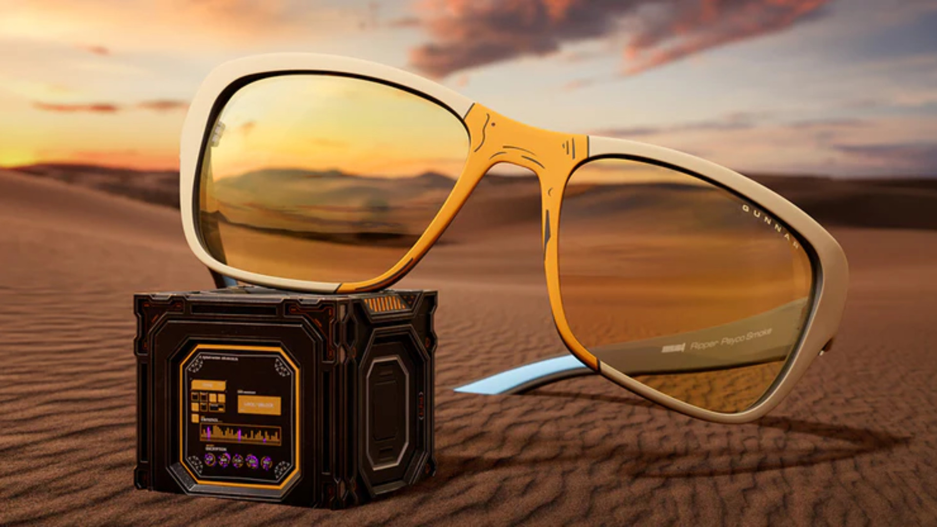 Eine gelbe Blaufilterbrille liegt im Sand auf einem Kästchen.