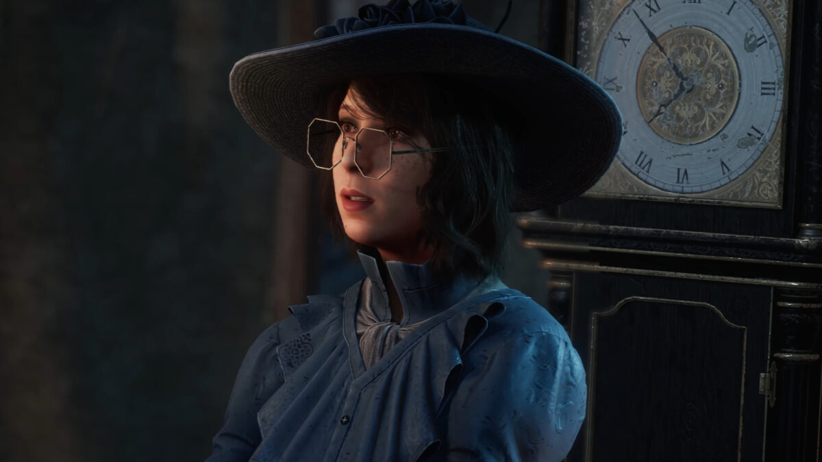 Eine Frau mit Brille, großem Hut und blauem Kleid.