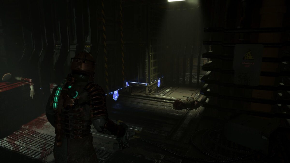 Isaac steht in Dead Space for zwei großen beweglichen Containern mit blauen Lichtern.