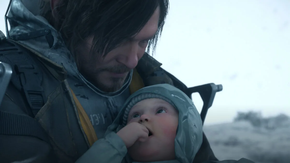 Ein Mann mit langen Haaren hält ein kleines Baby im Arm.