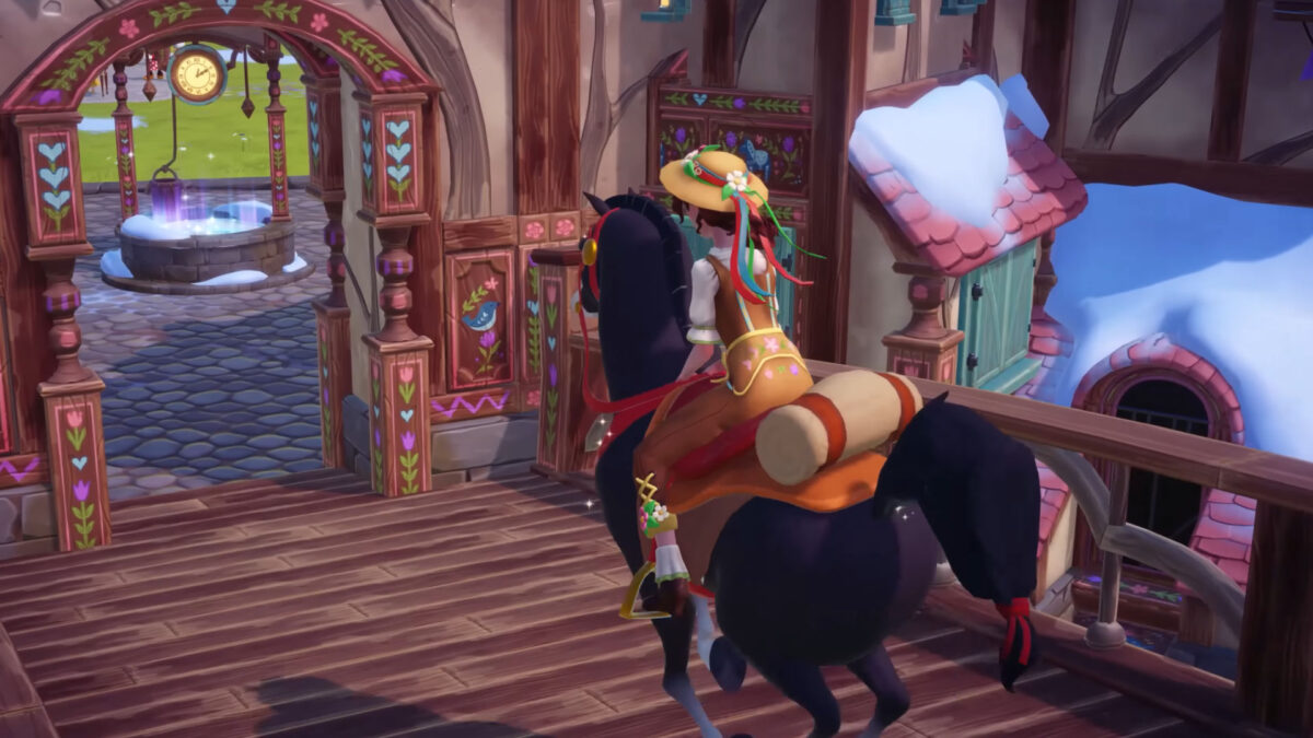 A girl wearing a hat sits on a black horse and rides through a gate.