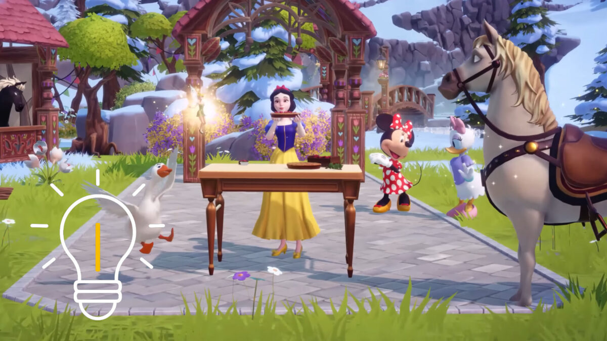 Snow White is standing at a table with Minnie Mouse and Tinkerbell, holding something up.