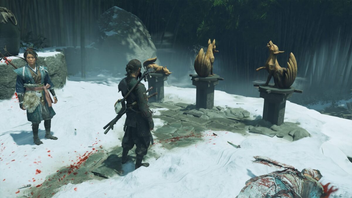 Atsu stands before three statues, with several blood splatters from enemies on the ground.