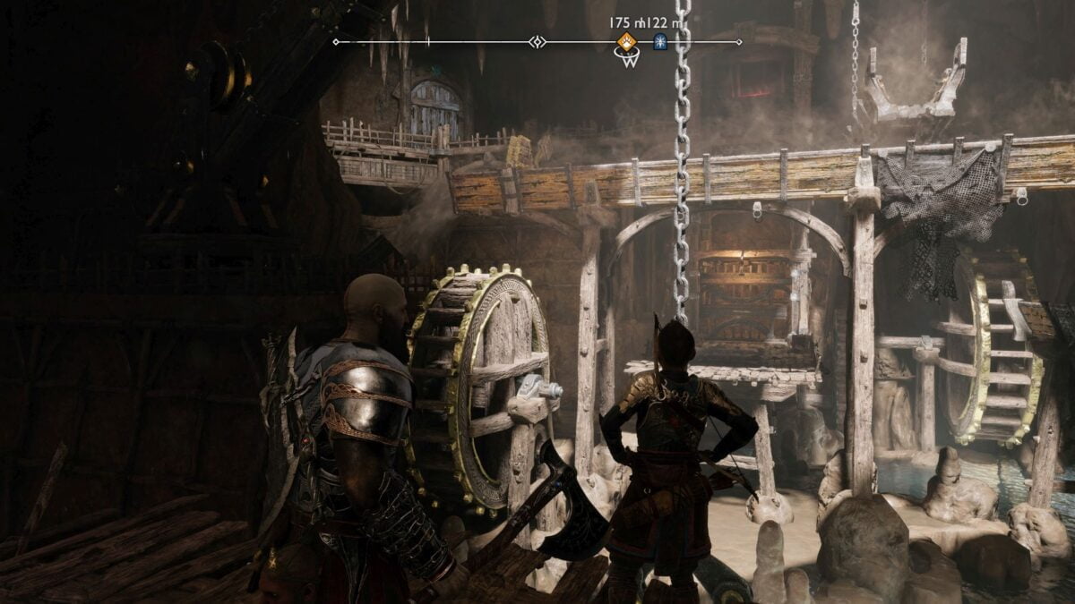 Atreus und Kratos stehen in God of War Ragnarök vor einem Aufzug und zwei hölzernen Wasserrädern.