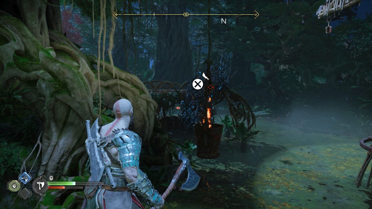 Kratos steht in God of War Ragnarök vor einer in einem Eimer befestigten Fackel, die über einem Sumpf hängt.
