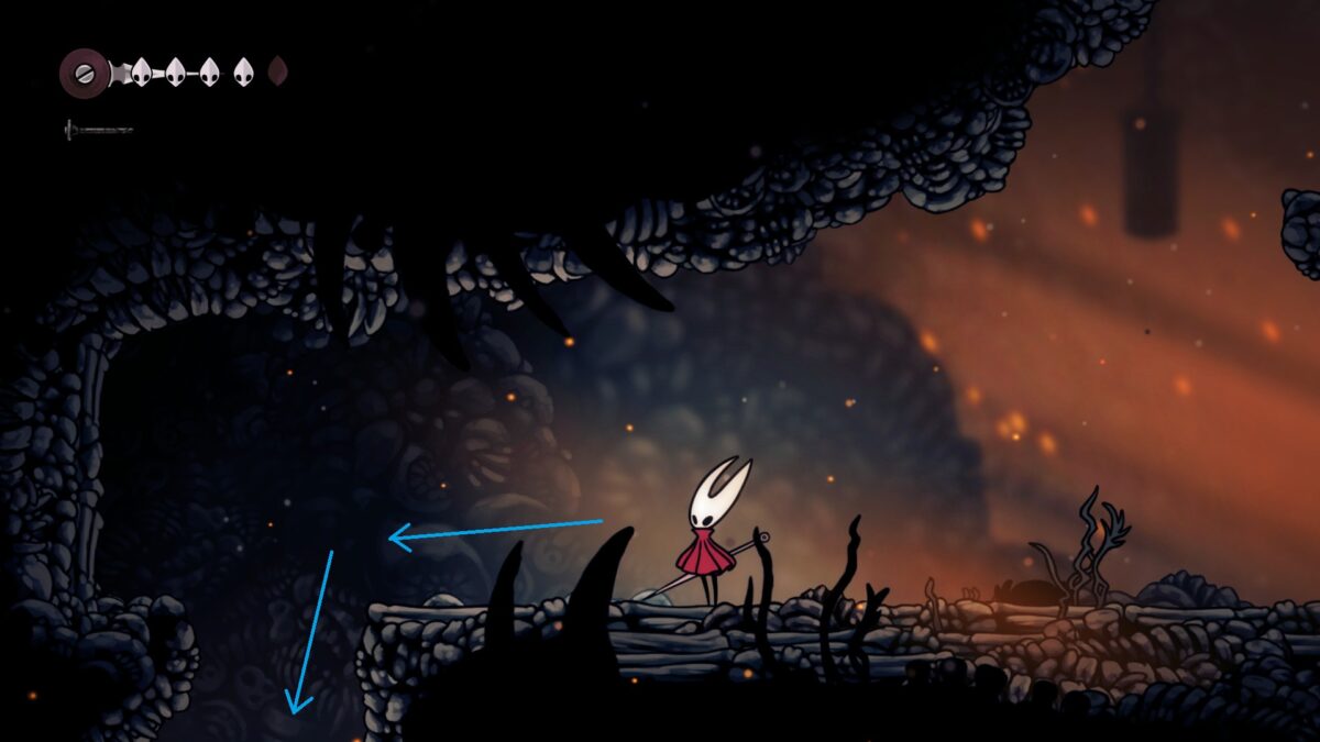Hornet stands in a cave, looking at a passage leading downward.