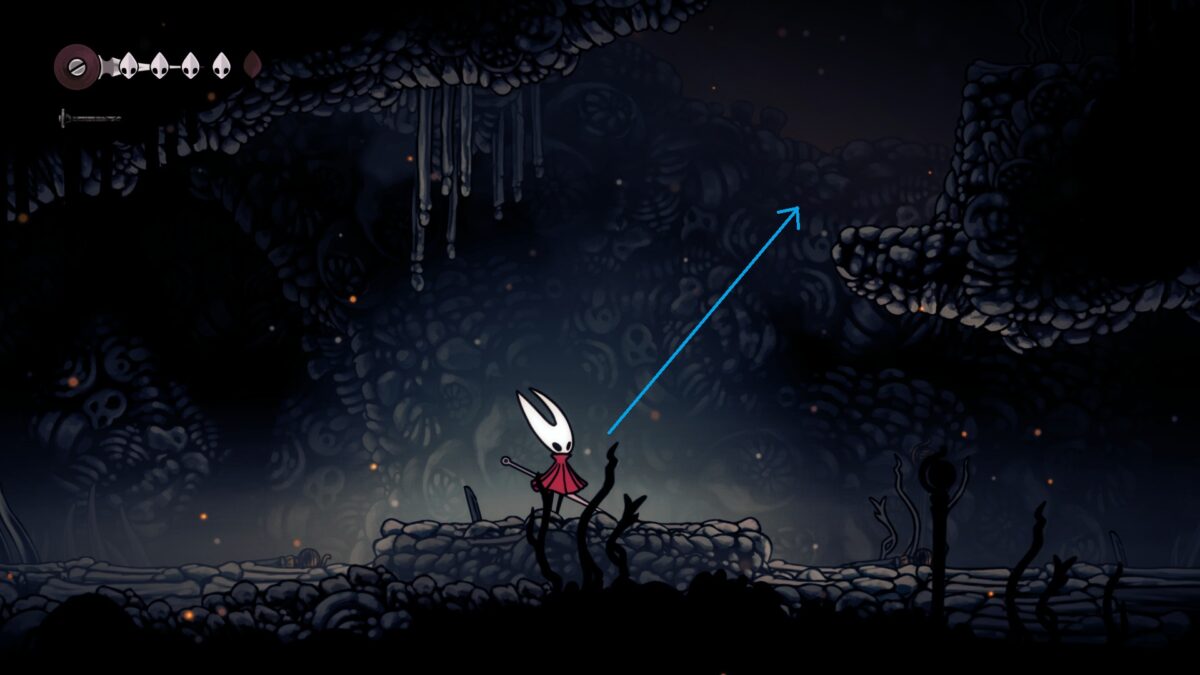 Hornet stands in a chamber filled with rocks and stones.