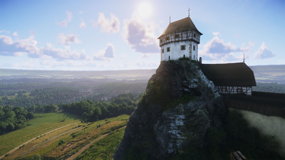 Eine Burg auf einem Felsen. Im Hintergrund sind grüne Wiesen und ein leicht bewölkter Himmel zu sehen.