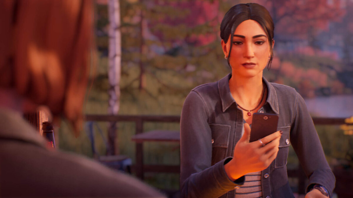 Safi sitzt mit einem Telefon in der Hand an einem Tisch, davor Max.