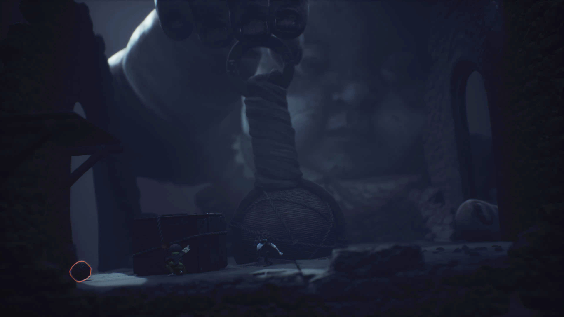 A Giant Baby lifts a massive rattle while two masked children hide behind it.