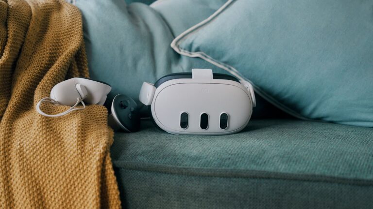 Die VR-Brille Meta Quest 3 liegt zusammen mit einem Controller auf einer grünen Couch.