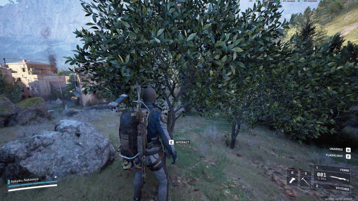 Ein Spieler steht mit ausgerüsteter Waffe und Rucksack vor einem Olivenbaum in einer hügeligen Landschaft; im Hintergrund sind Gebäude und aufsteigender Rauch zu sehen – Spielszene aus ARC Raiders.