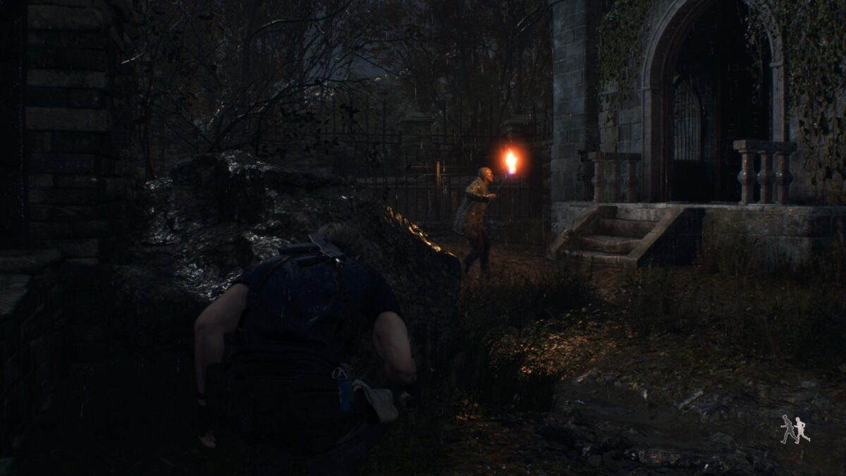 Leon versteckt sich in Resident Evil 4 Remake vor einem Dorfbewohner mit einer Fackel in der Hand.