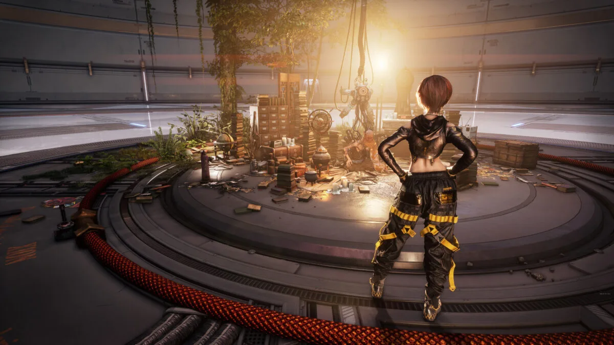 Ein älterer Mann, halb Mensch - halb Roboter, sitzt am Boden zwischen vielen Kisten und Gegenständen.