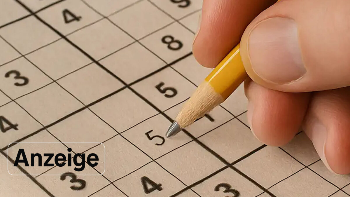 Eine Hand mit einem gelben Bleistift, die ein Sudoku-Feld ausfüllt.
