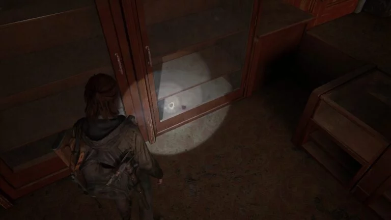 Sammelkarte am Boden eines Schrankes hinter Glas, im Foyer des Theaters in The Last of Us 2