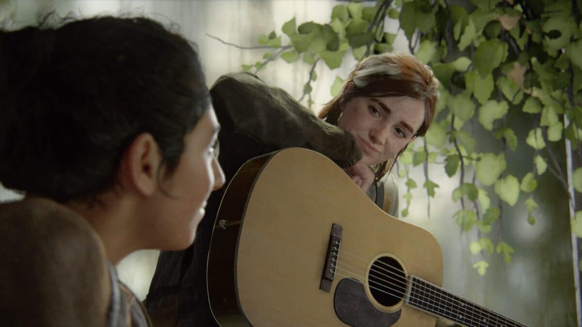 Ellie hält eine Akustik-Gitarre auf dem Schoss und lächelt ihre Freundin Dina in The Last of Us Part 2 an.