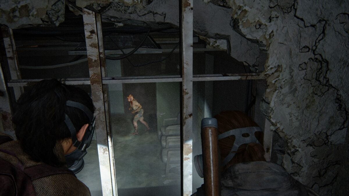 Ellie und Dina beobachten in The Last of Us Part 2 einen Clicker, wie er im Raum unter ihnen umherstreift.