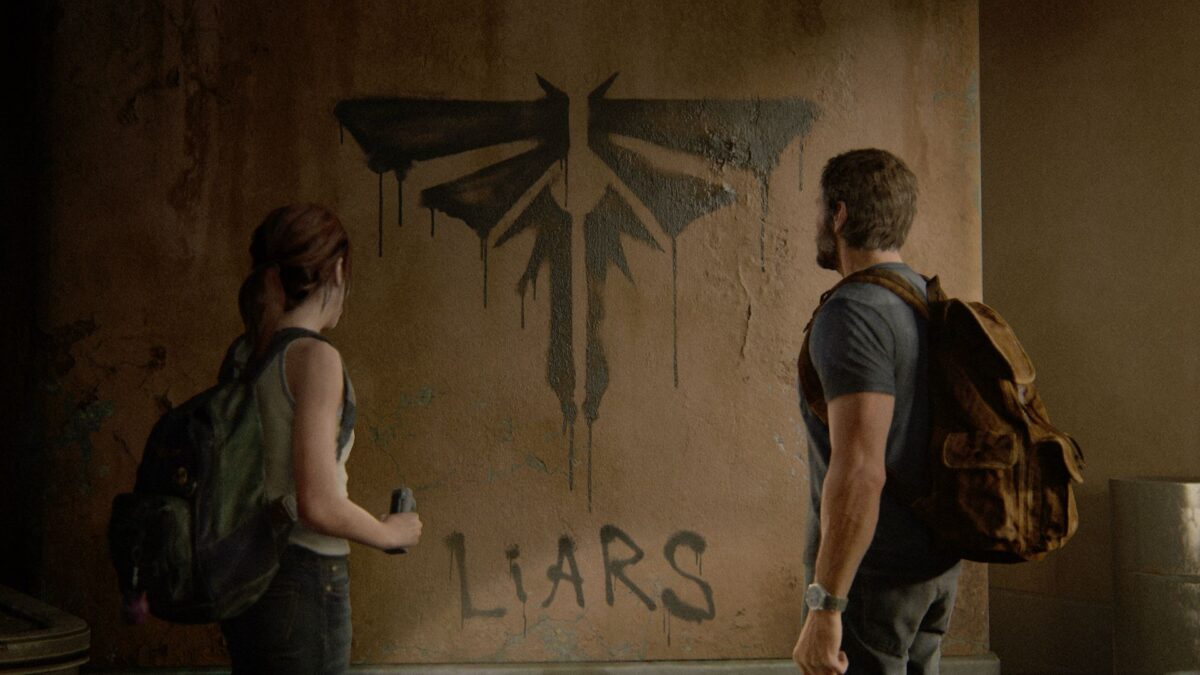 Ellie und Joel stehen in The Last of Us Part 2 vor einem Graffiti, das die Fireflys verunglimpft. 
