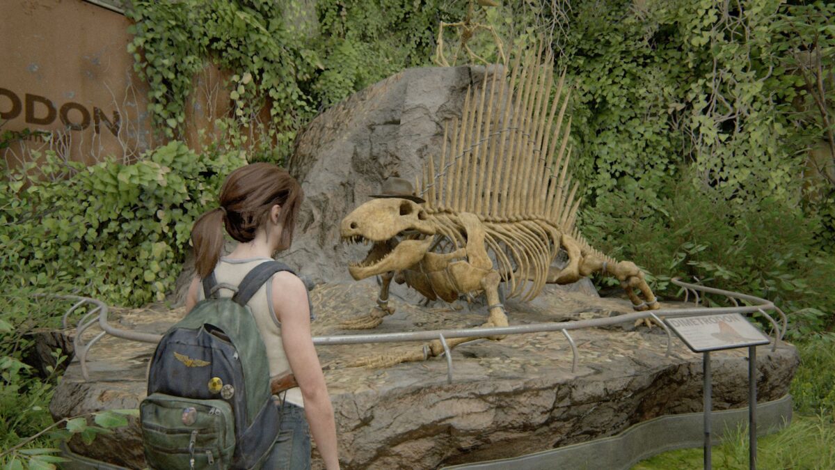 Ellie steht in The Last of Us Part 2 vor einem Dinosaurierskelett, dem sie einen Hut aufgesetzt hat.