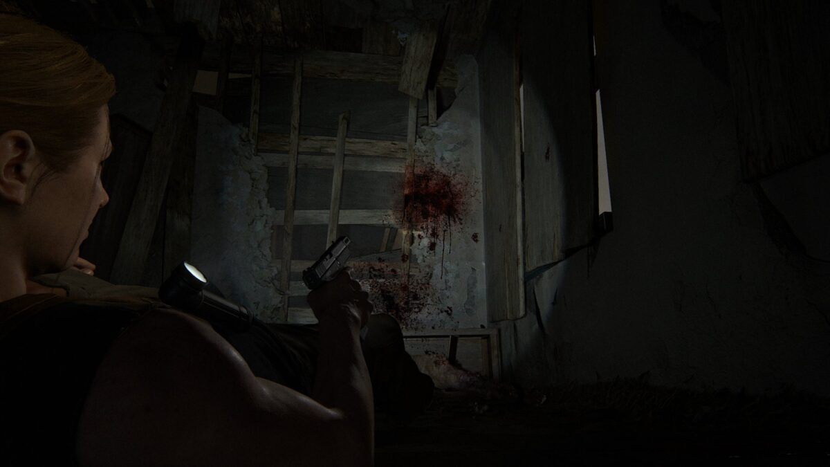 Abby liegt in The Last of Us 2 mit gezückter Waffe am Boden und blickt auf einen Blutspritzer.