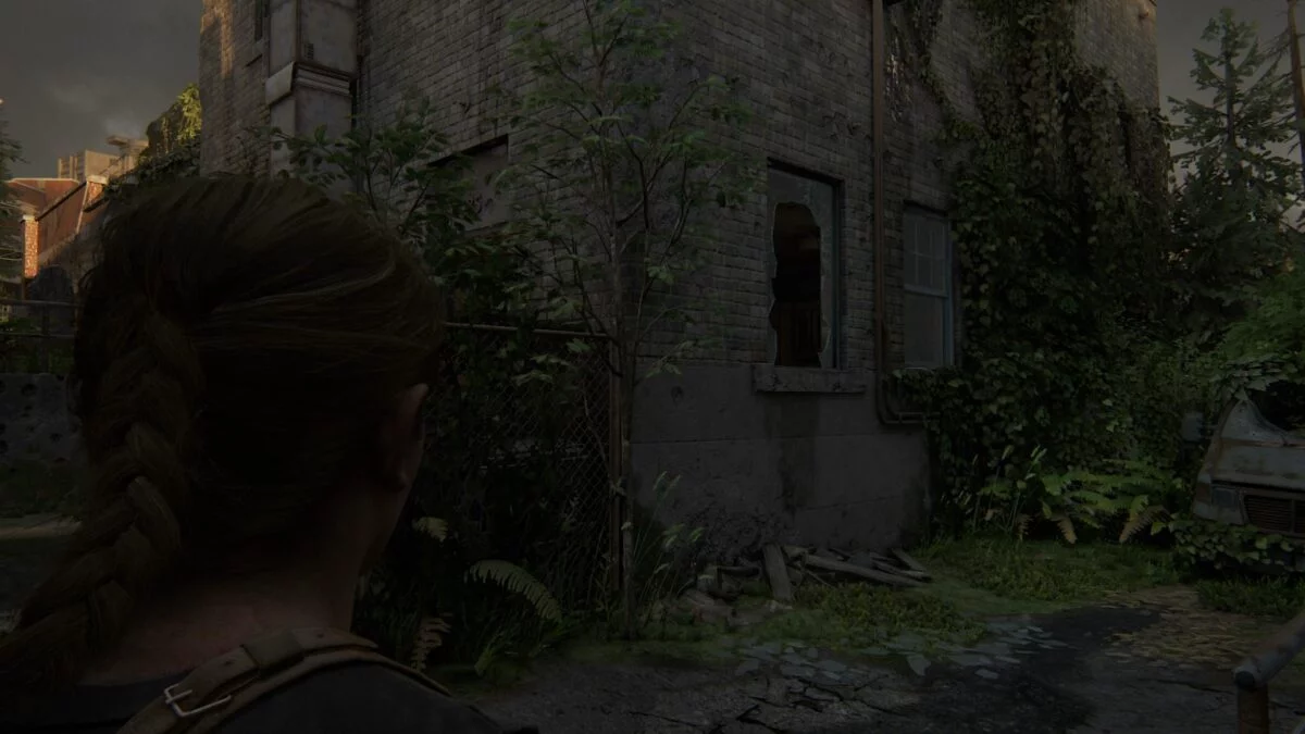 Abby steht in The Last of Us 2 vor einem zerbrochenen Fenster.