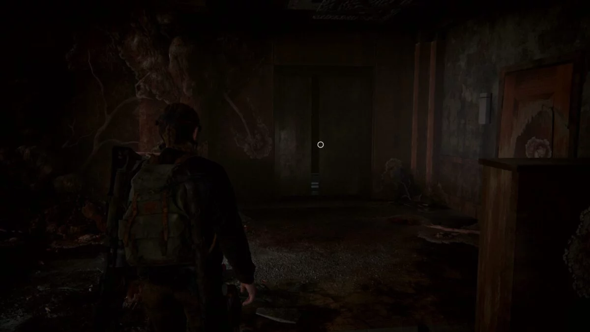 Abby steht in The Last of Us 2 im Hotel-Flur vor einem Aufzug.