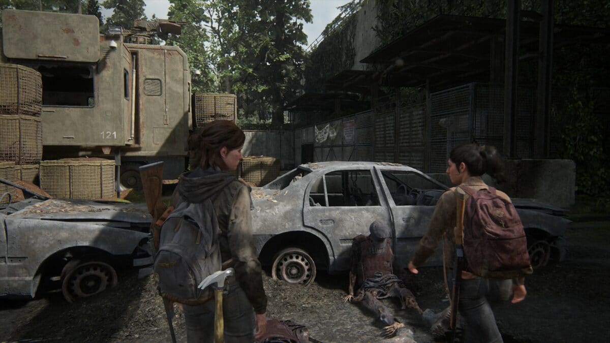 Dina und Ellie auf dem äußeren Vorplatz zum Tor mit Autowracks und Leichen