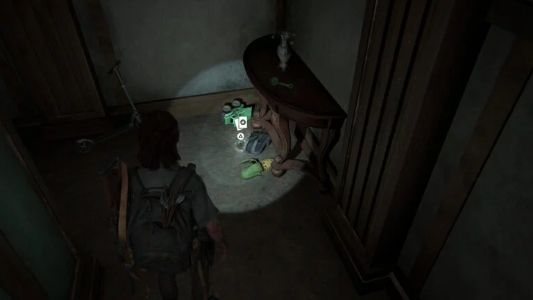 Die Sammelkarte Doppelganger neben einem Rucksack und zwischen Spielsachen auf dem Flur in The Last of Us 2