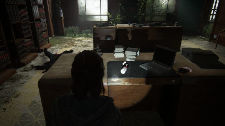 Auf dem Schreibtisch neben dem Laptop im Richterzimmer des Gerichts in The Last of Us 2 liegen Zusätze.