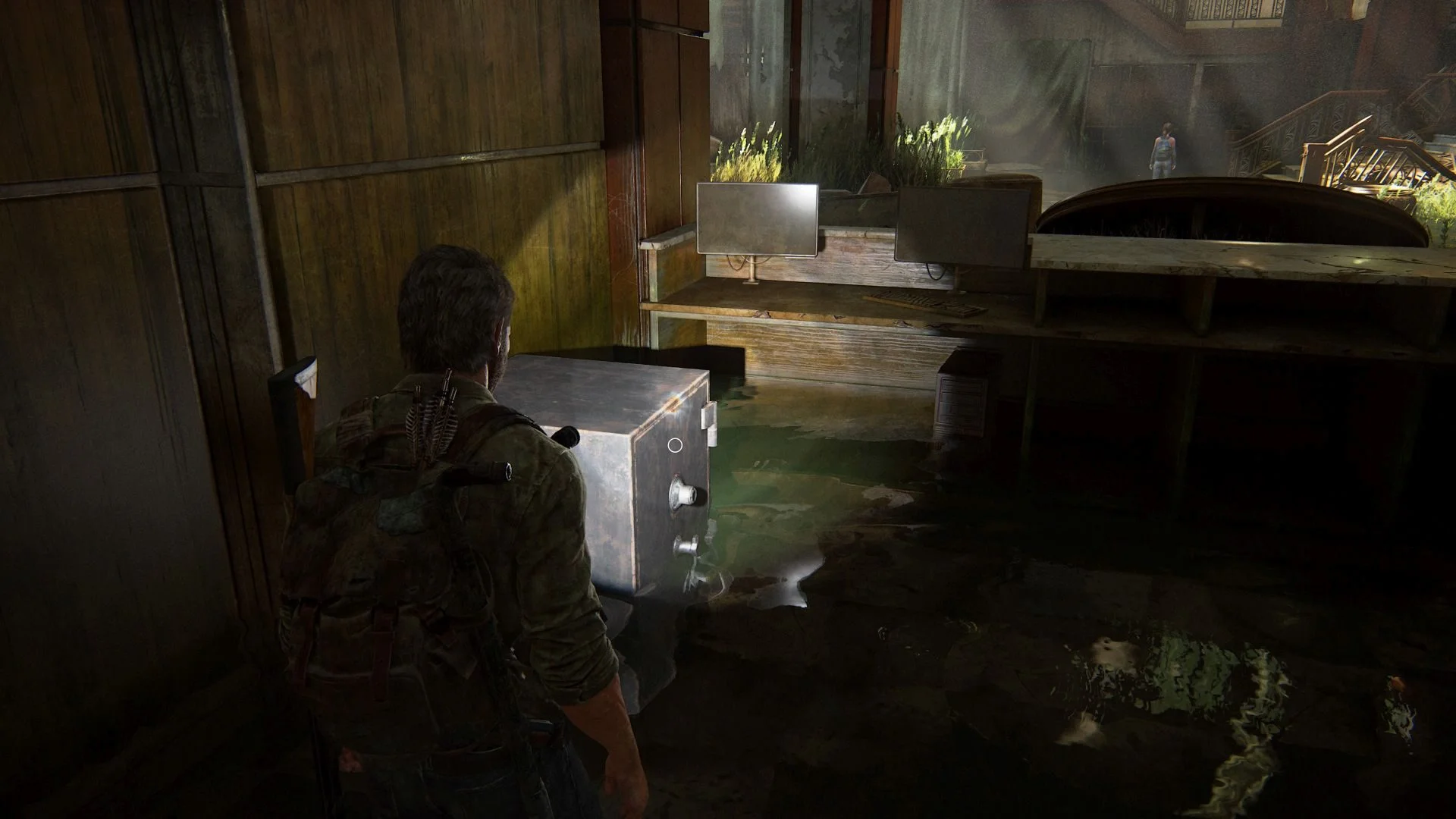 Joel steht in The Last of Us Part 1 vor einem Safe in der Hotellobby.