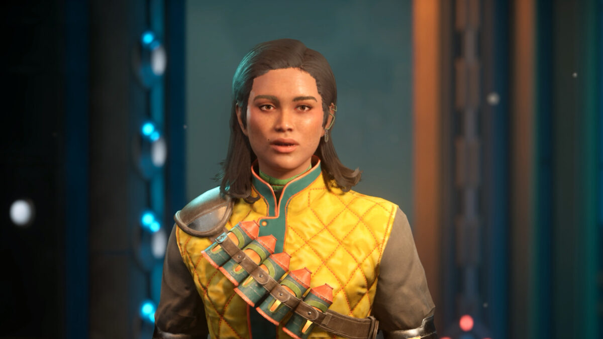 Eine Frau mit mittellangen dunklen Haaren trägt eine gelb gesteppte Jacke mit Patronengurt und blickt direkt in die Kamera – Spielszene aus The Outer Worlds 2.