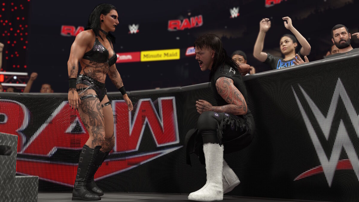 Eine Szene aus einem Wrestling-Match in WWE 2K25 zeigt eine muskulöse Frau, die dominant über einem knienden Mann mit schmerzerfülltem Gesicht steht.