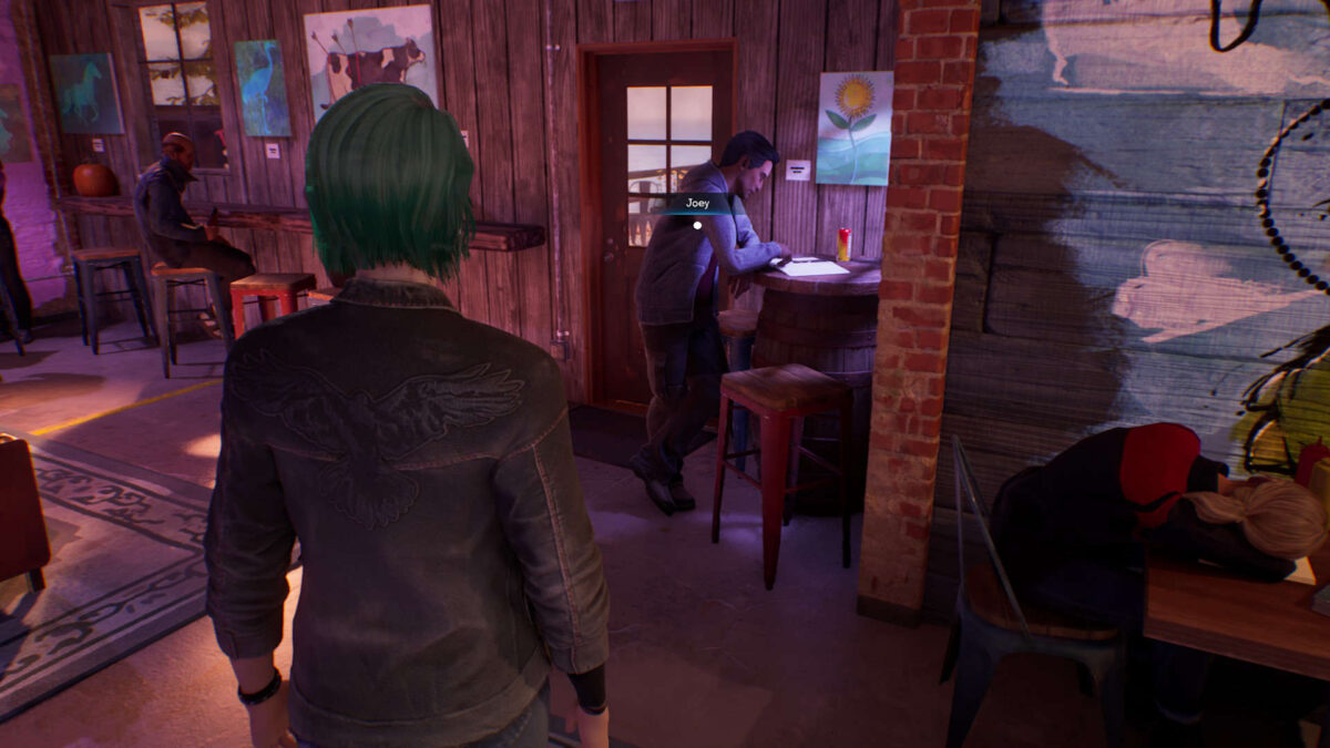 Chloe steht vor einem Mann, der an einem Bartisch lehnt.